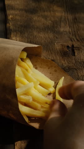 Vertical video. Fast food concept. Person eating french fries. 