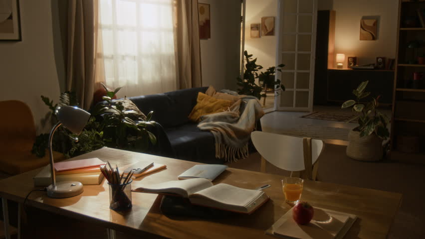 No people interior shot of books left open, juice half-full, and blankets rumpled on couch in peaceful, sunlit room