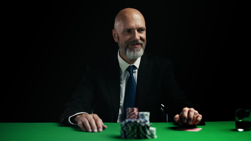 Smiling businessman going all-in during poker game, pushing stacks of chips