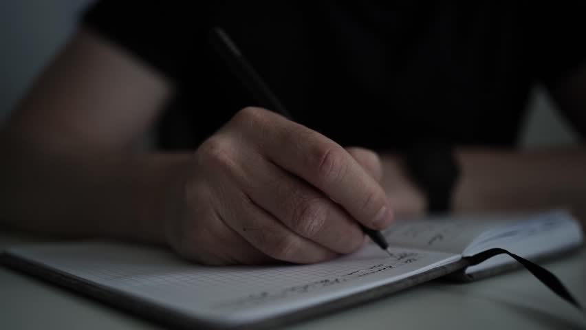 man journaling his thoughts into notebook, because he has some sort of depression, problems and want to find out and help himself without psychologist