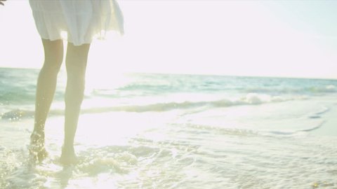 Legs feet Hispanic girl walking barefoot wet sand island beach sun lens flare shot on RED EPIC