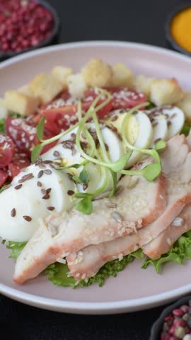 Bowl with caesar salad with chicken, parmesan cheese, tomatoes, croutons, lettuce leaves, flax seeds, sunflower and sesame seeds
