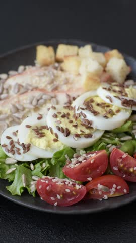 Bowl with caesar salad with chicken, parmesan cheese, tomatoes, croutons, lettuce leaves, flax seeds, sunflower and sesame seeds