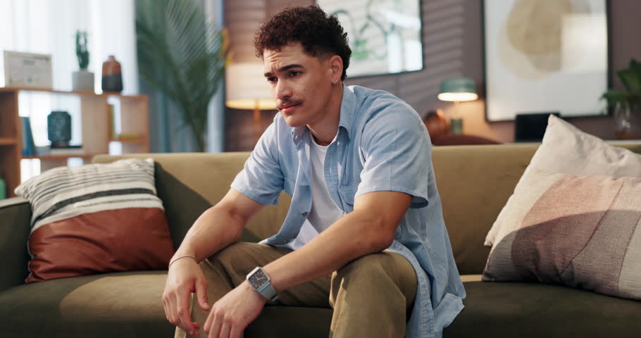 Anxiety, man and nervous on sofa in home with stress, trauma or stimming with overthinking. Mental health, worry or person with depression in lounge with fear, emotions or overwhelmed by panic attack