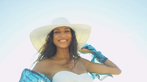Young Hispanic beach girl wearing white swimsuit straw hat having fun smiling to camera on beach sun lens flare close up shot on RED EPIC