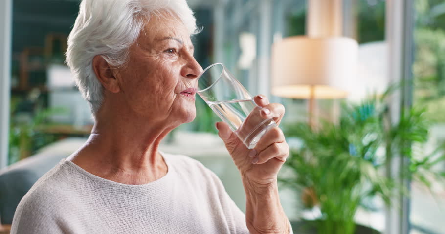 Thinking, water and senior woman in home for wellness, health and nutrition in living room for calm. Retirement, drinking and elderly person with liquid for thirsty, hydration or detox for reflection