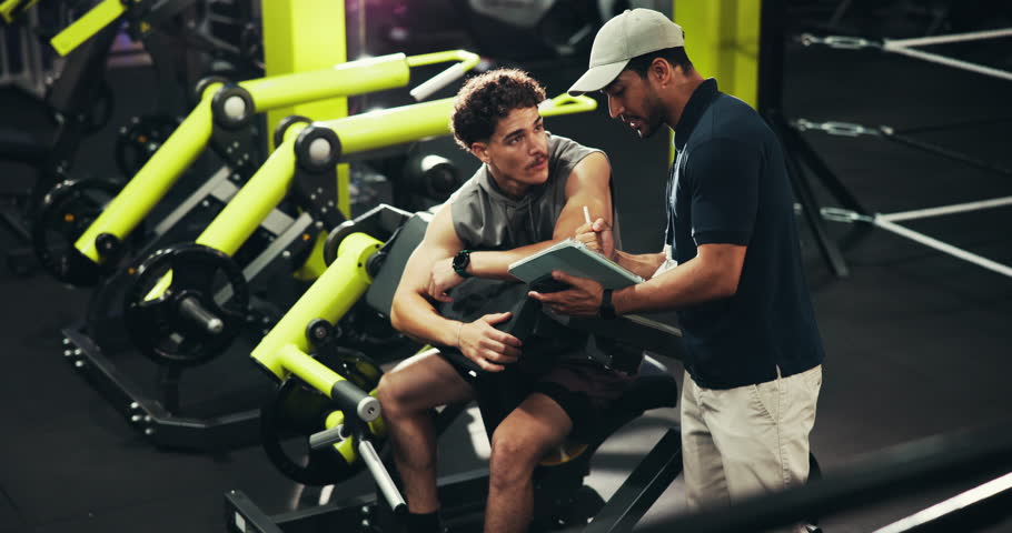 Tablet, fitness and men in gym, fist bump and support with challenge, training and personal trainer. People, instructor and bodybuilder with tech, hand gesture and app for progress or exercise goals