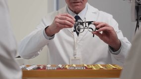 Close up on hands of mature male ophthalmologist holding trial frames consulting patient on prescription glasses while changing dioptric lenses during appointment at eye care clinic - Powered by Shutterstock - Get 15% off with code: PIKWIZARD15