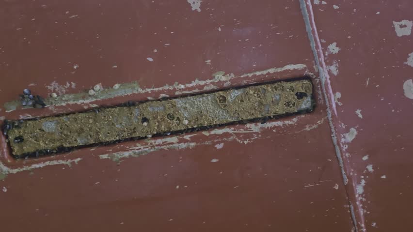 Zinc anode flush with ship hull appears worn and dirty during inspection in drydock. Anti corrosion use.