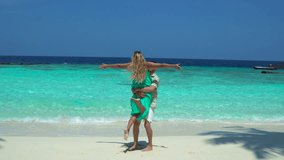 A couple spins around joyfully on a beach in the Maldives, with turquoise water and sandy shore in the background. - Powered by Shutterstock - Get 15% off with code: PIKWIZARD15