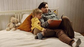Happy old grandmother reading book to curious grandson indoors. Grandma with grandchild spending time together. Multi generation family. Kid boy and senior woman read story lying in bed. Elderly lady - Powered by Shutterstock - Get 15% off with code: PIKWIZARD15