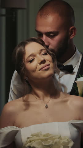Wedding couple sharing an intimate moment in a hallway. A wedding couple embraces in a warmly lit hallway, with the groom gently kissing the brides forehead as she smiles.