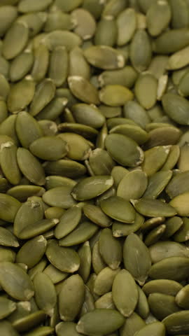 Peeled green pumpkin seed taking with golden spoon, close up