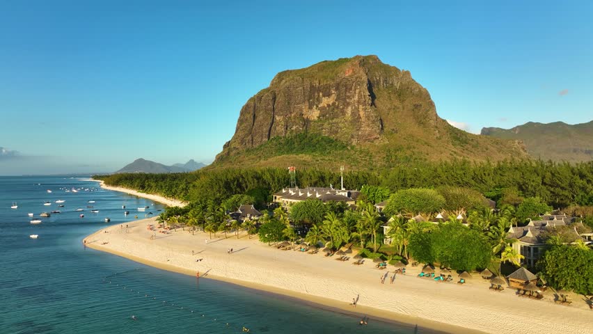 Aerial view of Le Morne Brabant mountain towering over a luxury beachfront resort with boats, white sand, and turquoise ocean