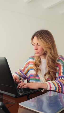 A stressed woman with long hair is visibly frustrated while working on her laptop. She holds her forehead in distress, showcasing the struggle of managing work-related problems and overwhelming stress