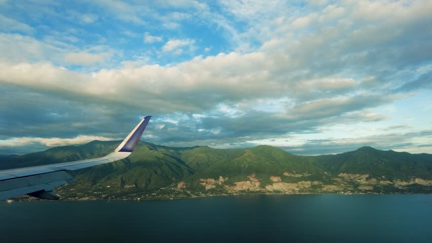 A view of the mountains with houses. Clear, cloudy morning weather. This view is seen from inside the cabin of an airplane ready to landing.