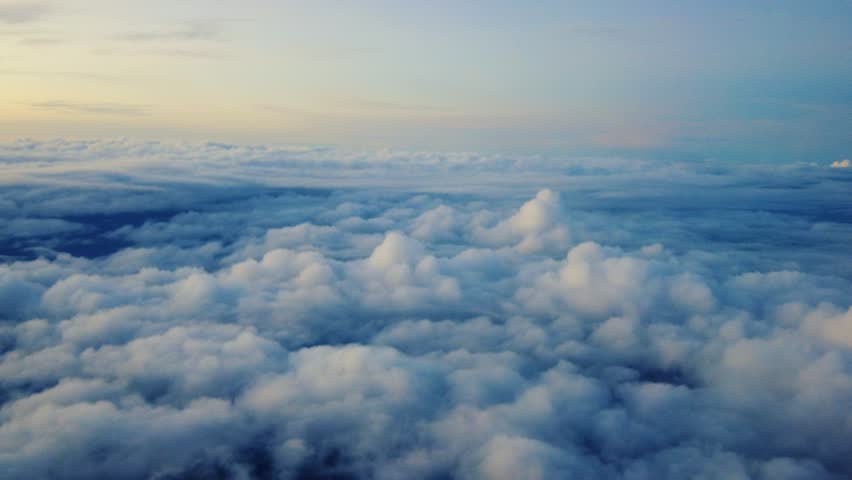 A collection of cumulus clouds as seen from inside an airplane cabin. The weather was clear in the morning.