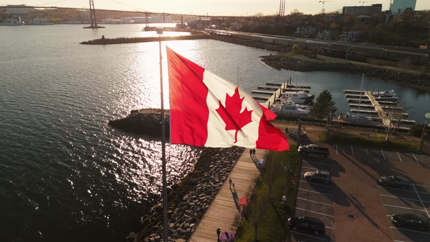 An Aerial View of the Canadian Flag Flying on the Dartmouth Waterfront with the Skyscrapers of Halifax in the Background. The Flag Waves in the Wind, Representing Canada Strength and Beauty.
