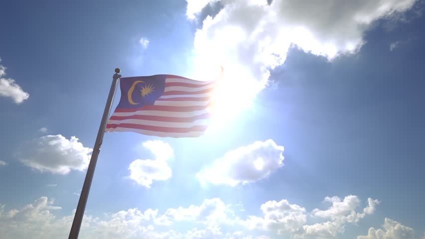 Malaysia Flag waving on a Flagpole from a Moving Angle in front of a blue sky with clouds