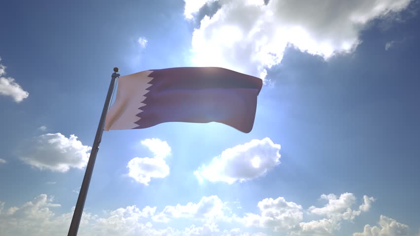 Qatar Flag waving on a Flagpole from a Moving Angle in front of a blue sky with clouds