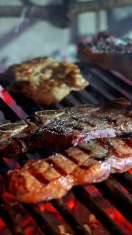 Professional chef seasoning delicious cuts of meat on a hot grill in a restaurant kitchen, preparing a flavorful meal