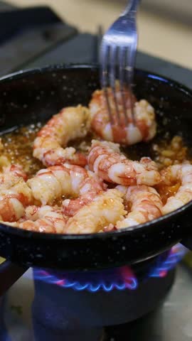 Professional chef expertly flipping succulent scampi in professional kitchen, sauteing seafood over intense gas flame with culinary precision