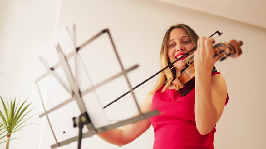 Young woman playing violin in elegant red dress