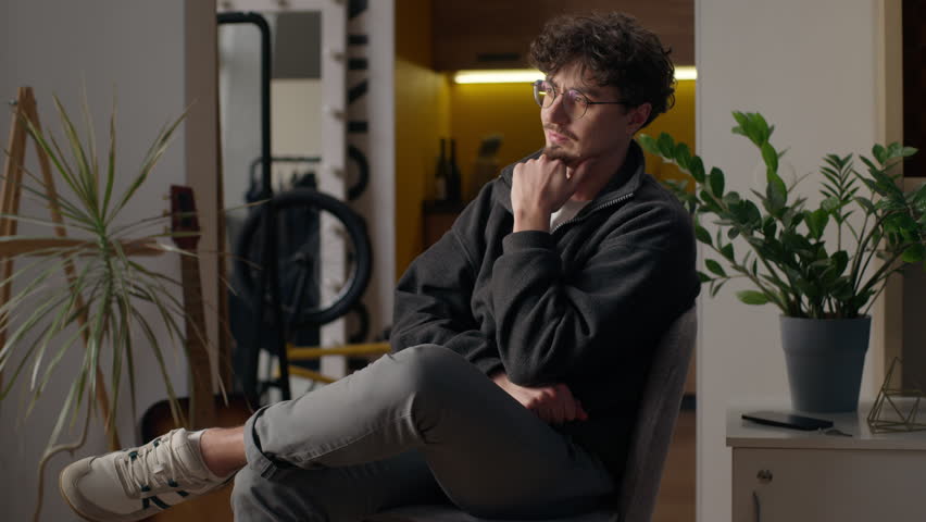Thoughtful Hispanic man sitting pondering at home handsome guy in eyeglasses contemplation searching solution pensive adult male posing apartment serious hipster thinking searching for solution indoor