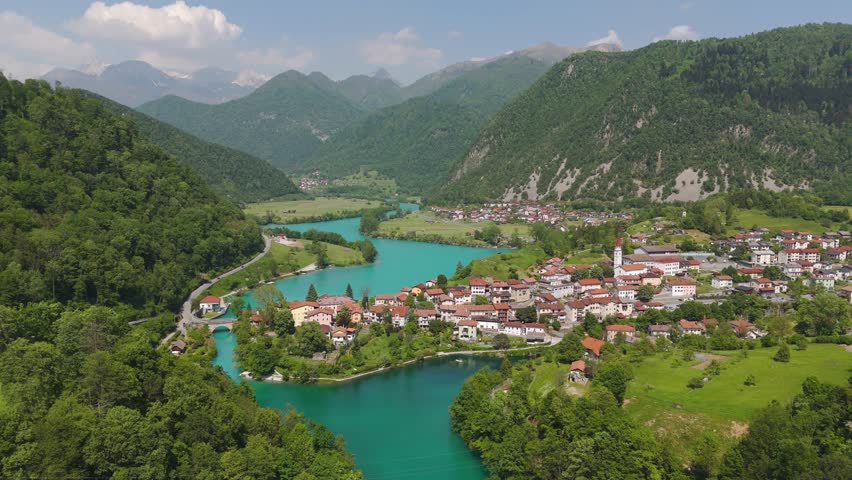 Drone establihsing orbit of vivid turquoise river and lush terrain near Most na Soci in Slovenia