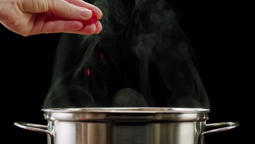 Professional chef adds paprika fragrant dry peppers to a pot of boiling food. Restaurant kitchen cooking, colorful spices, dropping spices.
