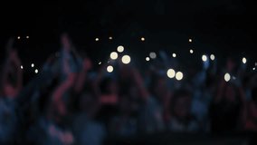 A stunning slow-motion footage of a large crowd at a night concert, waving hands and mobile phones with flashlights in the air. The audience follows the rhythm of the music, creating a magical and emo - Powered by Shutterstock - Get 15% off with code: PIKWIZARD15