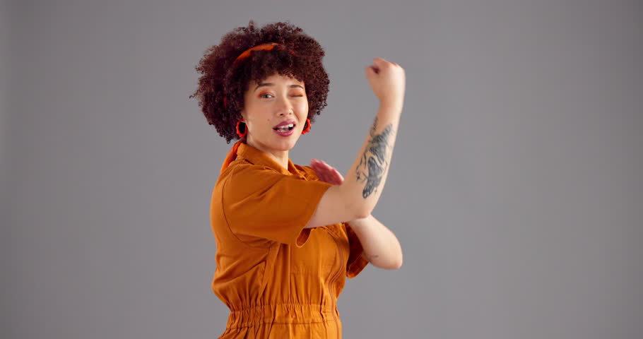 Flex, wink and face of woman in studio for empowerment, strength and confidence. Mockup space, champion and portrait of person with strong, arm or muscle for power, pride and happy on gray background