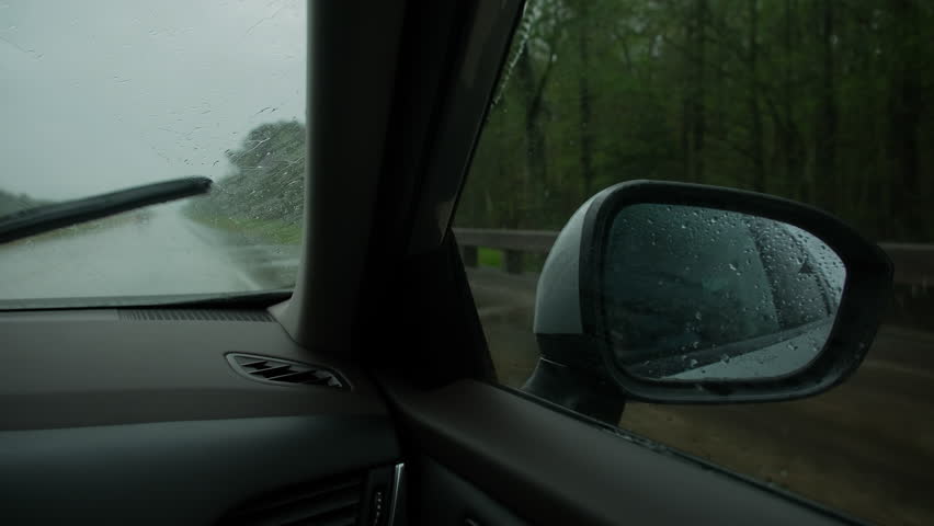 Driving car on highway road on rainy weather in spring. Side view from the front passenger seat