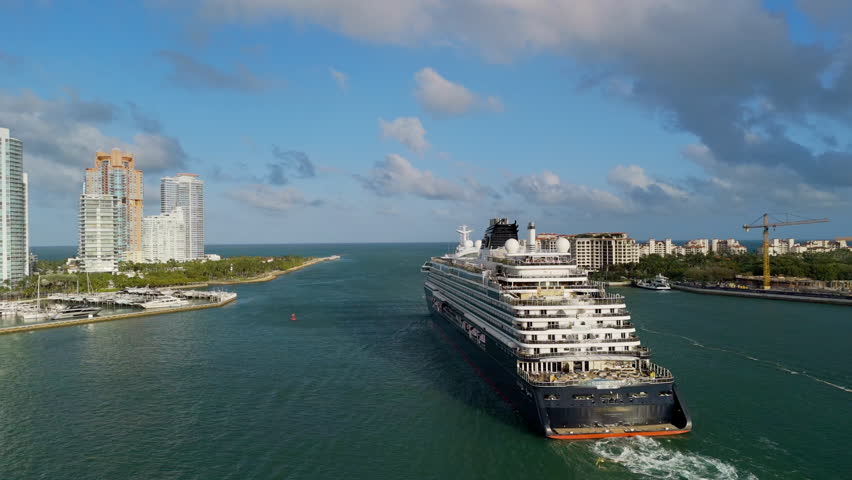 Large cruise liner departing from the Miami port on sunny bright day . Wide aerial view. 