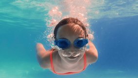 Underwater video sequence capturing young girl swimming, playing, and diving in pool with orange swimsuit and goggles, showcasing summer recreation and childhood joy - Powered by Shutterstock - Get 15% off with code: PIKWIZARD15