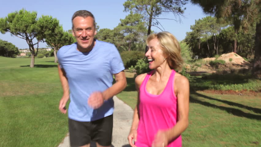 Senior couple in park jogging towards and then past camera position. Shot on Canon 5d Mk2 with a frame rate of 30fps