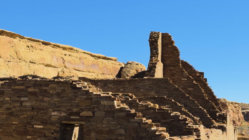 Ancient stone ruins of a pueblo structure with partial standing wall at Chaco Canyon, New Mexico.