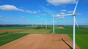 Row of spinning wind turbines generating clean energy over green and brown agricultural fields, sunny blue sky, white clouds, renewable energy, sustainability. Aerial drone lateral view - Powered by Shutterstock - Get 15% off with code: PIKWIZARD15