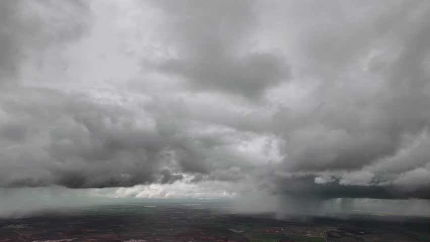 A threatening and darkening skies through the pilot eyes from a jet cockpit, flying through a turbulent sky plenty of storm clouds with intense rain showers ahead.