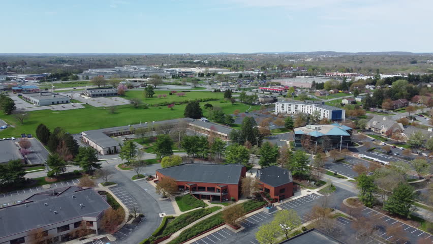 A sweeping drone pan captures both a Lancaster, PA commercial office park and neighboring residential community, with a vast backdrop of Lancaster County’s fields, rooftops, and springtime greenery.