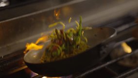 Capturing the dynamic motion of stir-frying vegetables in a flaming wok, showcasing a vigorous culinary technique. - Powered by Shutterstock - Get 15% off with code: PIKWIZARD15