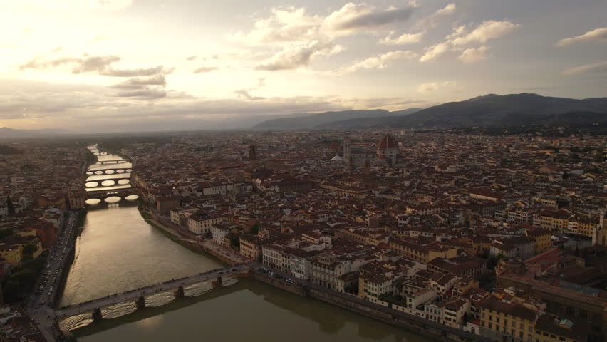 High aerial skyline of Florence with Ponte Vecchio at sunset, flying back