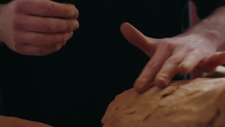 Close up of artist hands shaping a clay sculpture in a calm indoor studio setting