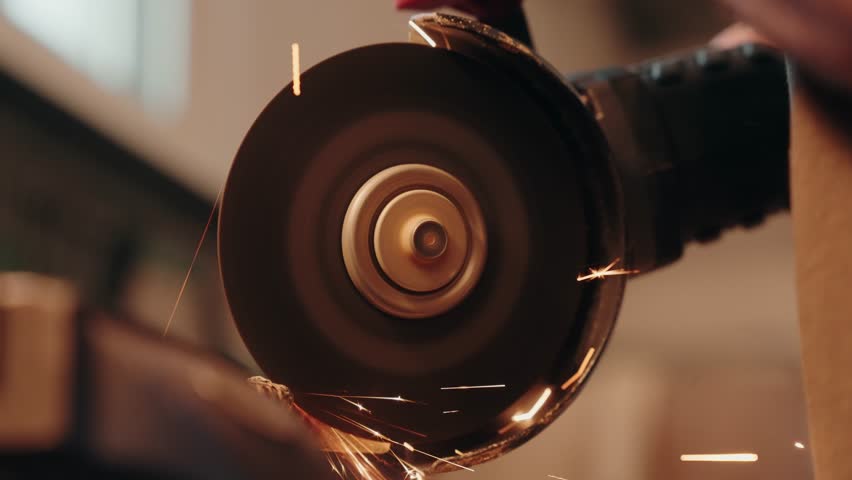 Close up of an angle grinder cutting metal with bright flying sparks in a workshop setting