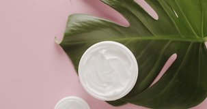 White Jars for cosmetics with tropical leaves Monstera on a pink background in studio.Glossy cosmetic jar with cream.Bottles skin care cream with tropical leaves Monstera for Beauty treatment. Natural - Powered by Shutterstock - Get 15% off with code: PIKWIZARD15