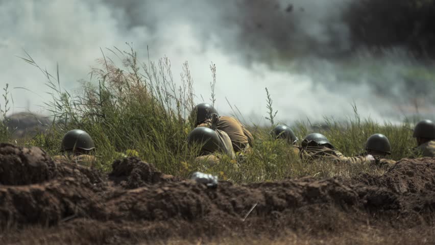Soviet Red Army soldiers holding defensive position in trench line amidst tall grass observing battlefield. Great Patriotic War battle reconstruction. Stress. Concussion probability Artillery shelling