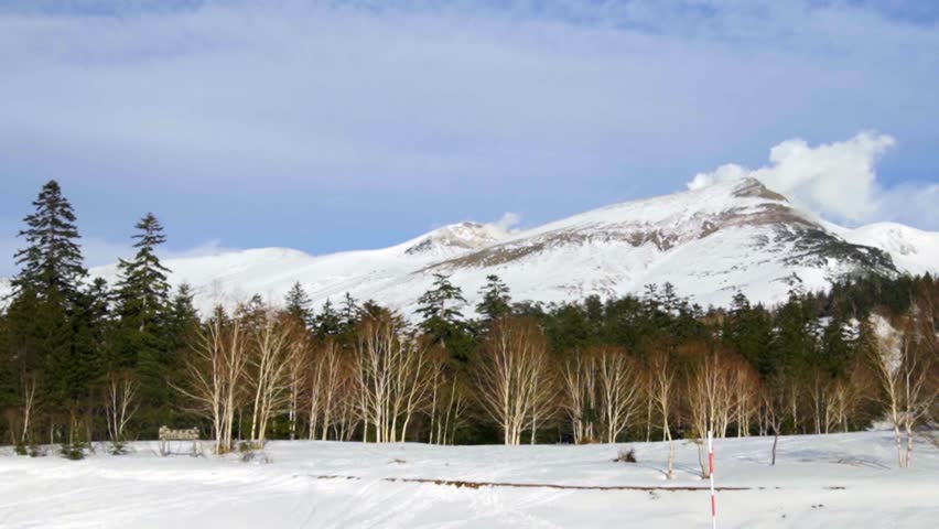 Snow-covered Tokachi Mountain Range seen from Biei, Hokkaido, Japan. The majestic peaks rise sharply under the clear winter sky, creating a powerful and serene mountain landscape.