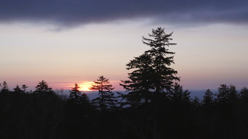 Beautiful sunset over the rural landscape of Biei, Hokkaido, Japan. Gentle light illuminates the rolling hills and farmland, creating a peaceful and atmospheric countryside scene.