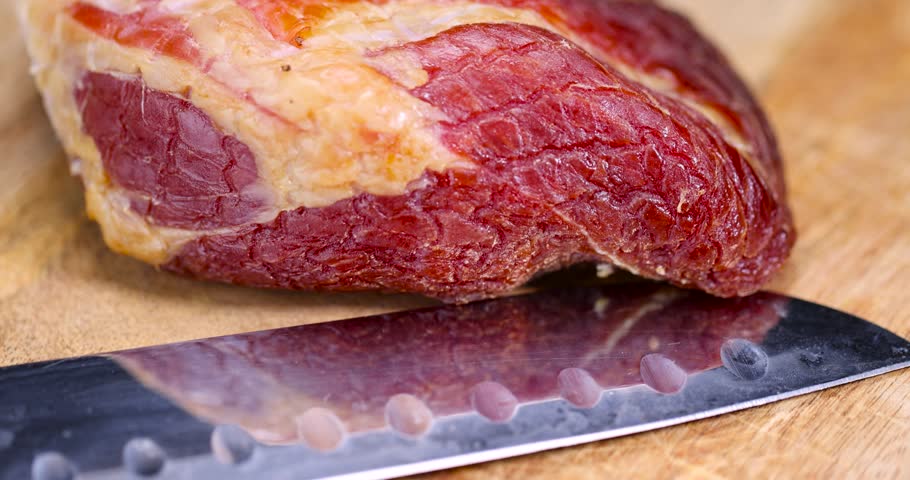 cured pork ham, a close-up of a piece of cured pork ham with thin layers of lard on the table