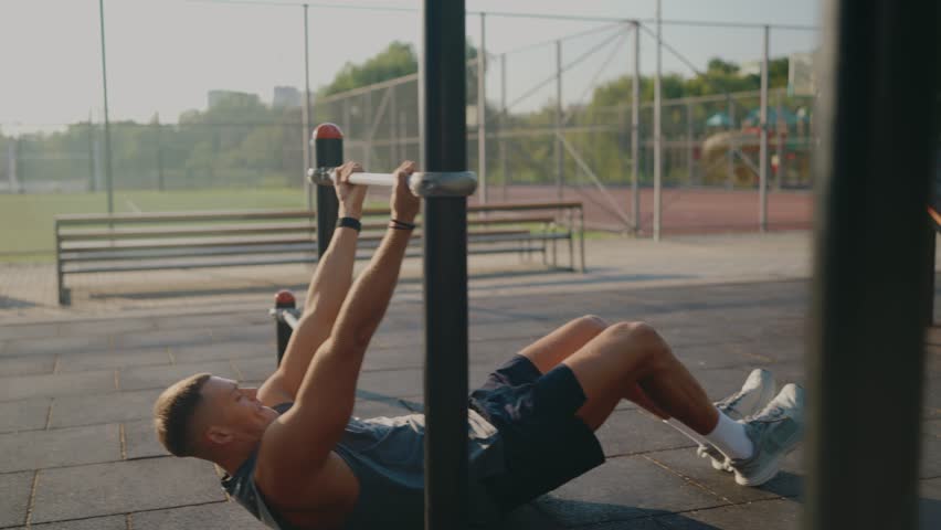 Fit young man performing outdoor bodyweight exercise on a sunny day, showcasing strength and dedication in a park setting. Young Man Exercising Outdoors with Bodyweight Training on Sunny Day